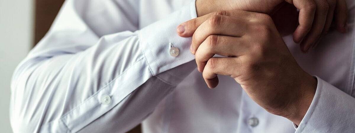 Businessman dress shirt. The man in the white shirt in the window dress cufflinks. Politician, man's style, Businessman buttoning his shirt,male hands closeup, American, European businessman